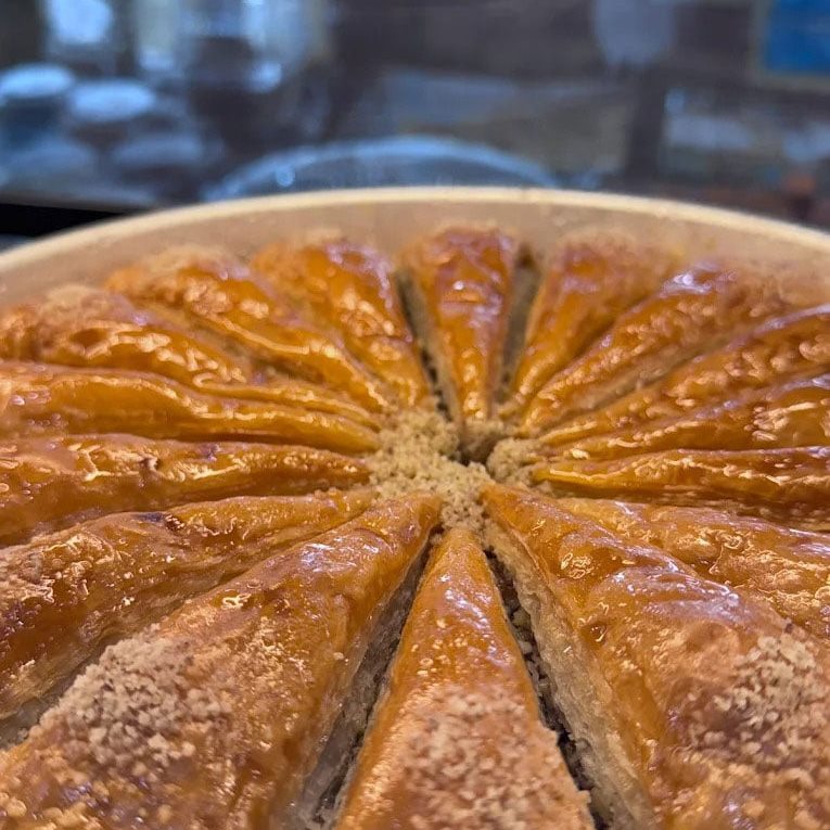 A full round tray of baklava, cut into wedges