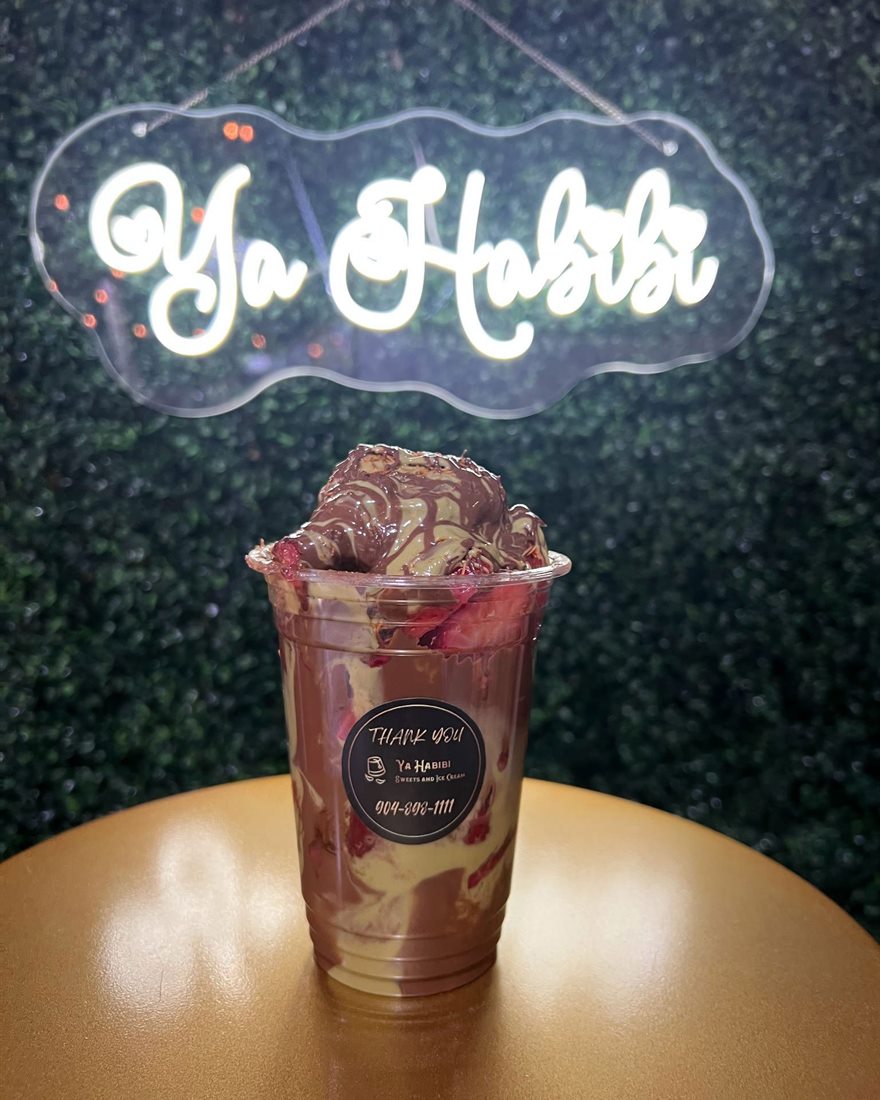 A layered dessert cup under the shop's neon sign