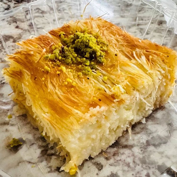 A close-up of golden knafeh topped with crushed pistachio